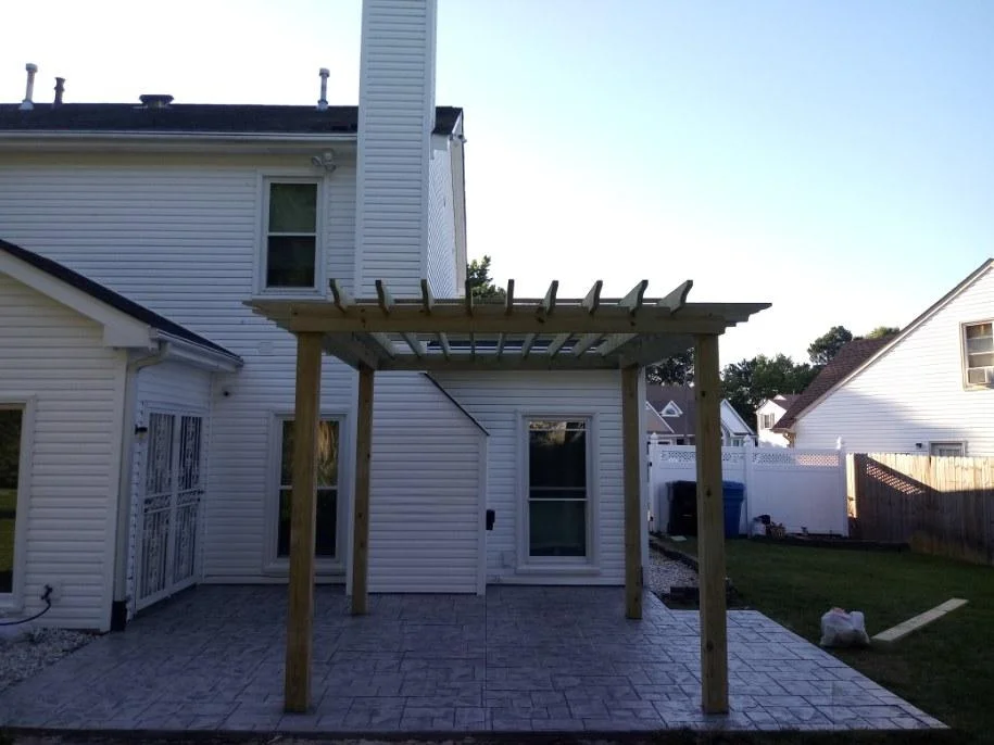 Finished stamped concrete patio with a cedar pergola behind a Chesapeake home