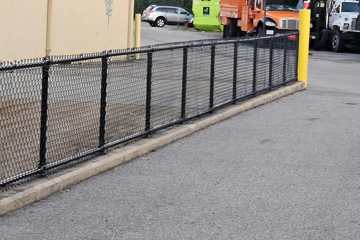 Black vinyl-coated chain link fence securing a Hampton Roads commercial lot