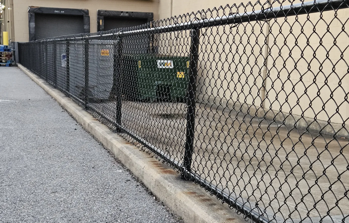 Black vinyl-coated chain link fence on a commercial service yard