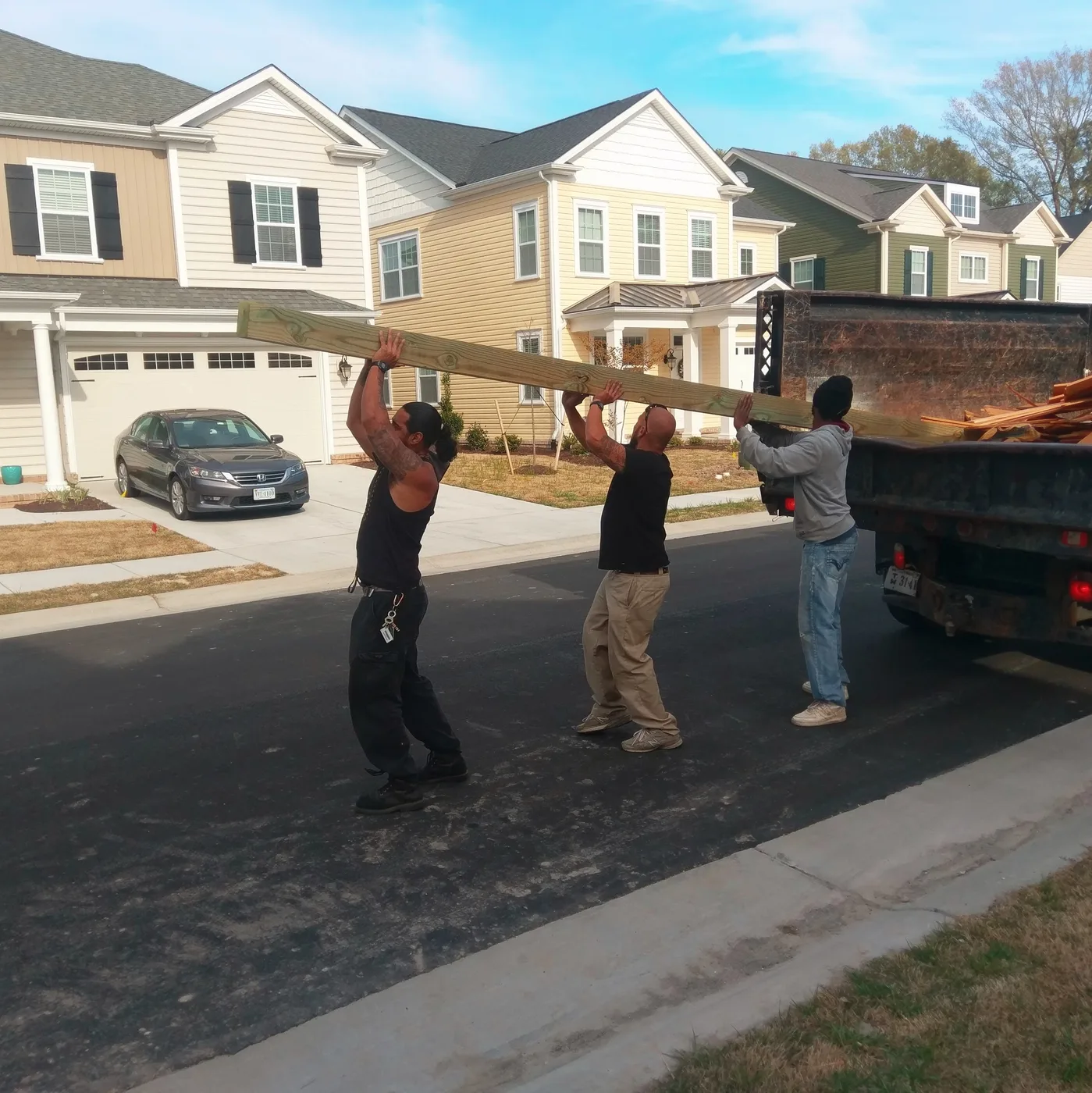 The boys walking a six-by-six off the trailer; every fence we sell is stick-built at your house, never prefab
