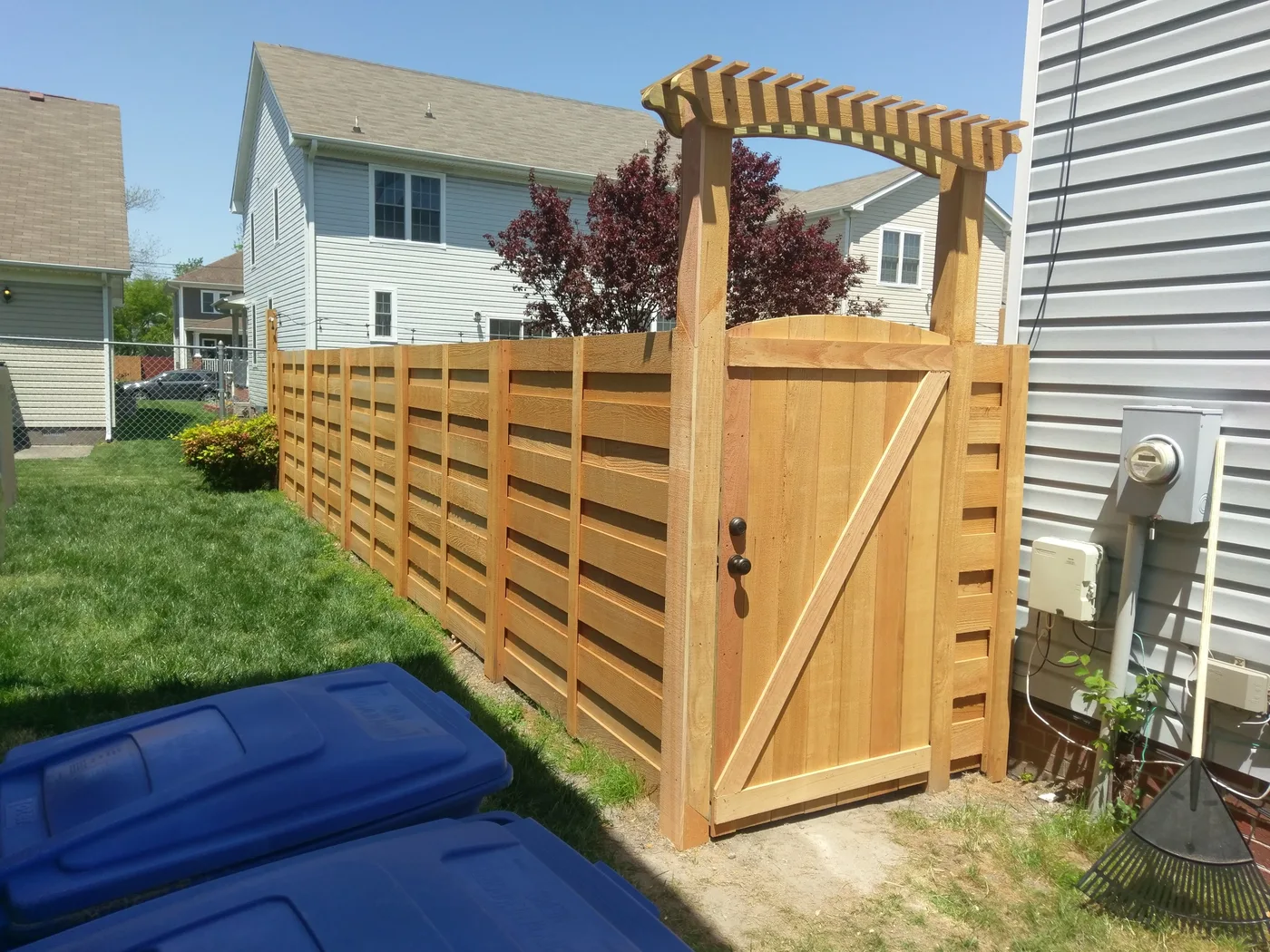 Horizontal cedar board-on-board run finished with an arched pergola-top walk gate