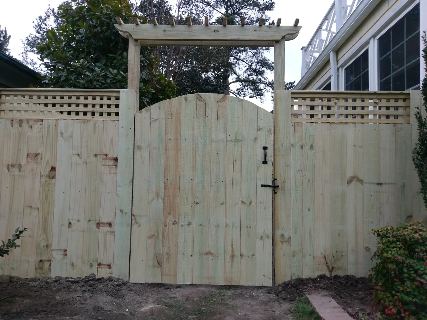 Wood privacy fence with square-lattice tops and an arched pergola-top walk gate, built by VB Fences