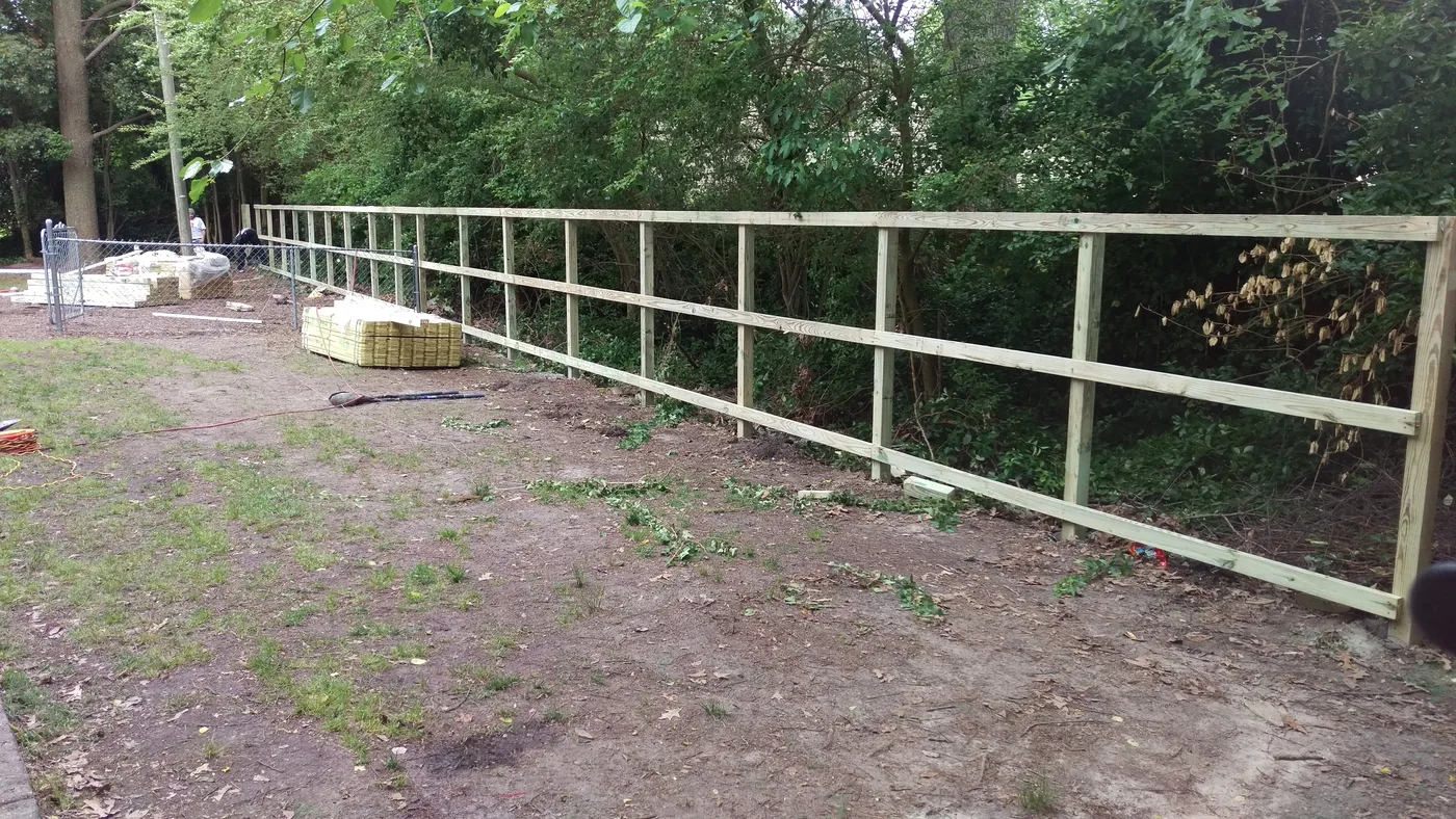 Three-rail post-and-rail fence line, set and leveled on site