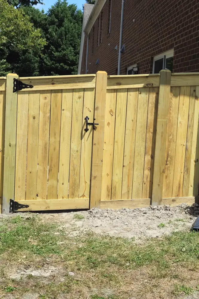 New 6-foot wood privacy fence with topcap trim and walk gate beside a brick home